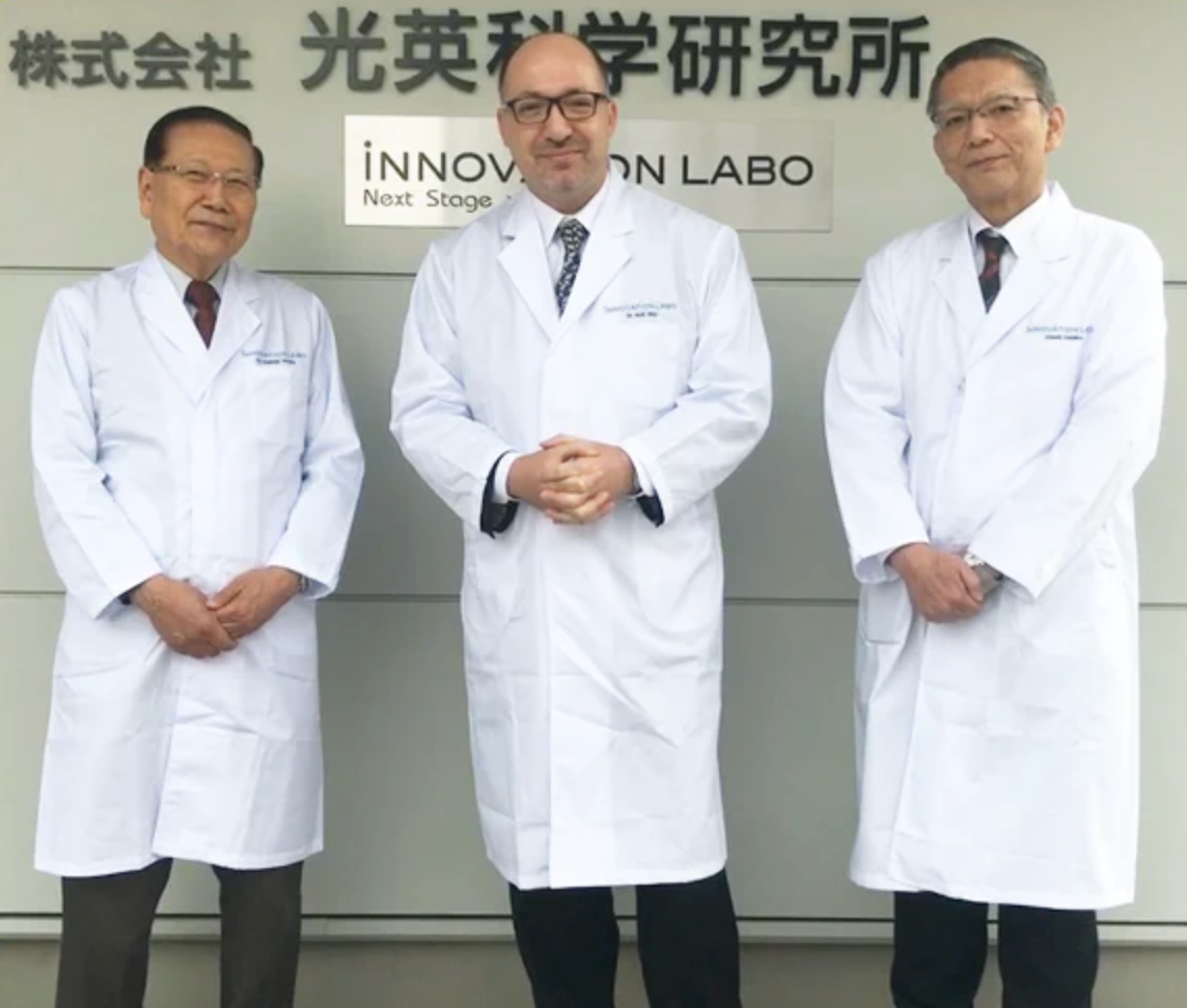 Doctors in white coats standing in front of a sign